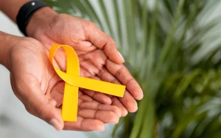 image illustrant deux mains tenant un ruban, symbole jaune de la lutte contre l'endométriose