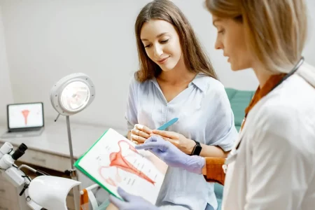 image illustrant une femme en consultation avec une gynécologue qui lui explique via un schéma d'utérus la pathologie et lui apporte des réponses pour l'article diagnostic de l'endométriose